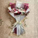 Bouquet of flowers wrapped in red and gold paper with a ribbon on a beige background